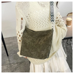 Détail du sac en velours côtelé vert olive avec une bandoulière tissée géométrique bicolore