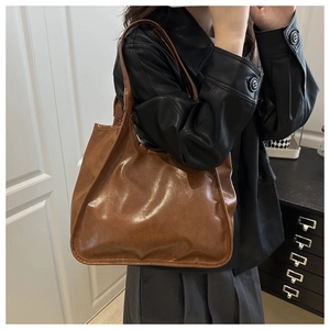 Side view of a vintage brown large tote bag with polished finish worn as a shoulder bag