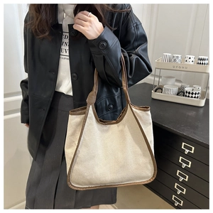 Detail of canvas tote bag showing dark brown leather trim and sturdy handle texture
