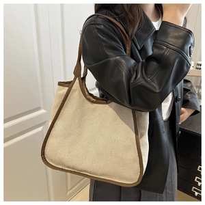 Close-up of beige canvas and brown leather trim on a large tote shoulder bag for women
