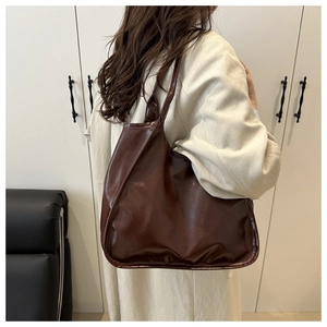 Rear view of a minimalist large brown leather tote bag worn as a shoulder bag