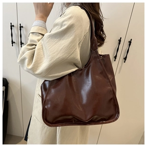 Detail of dark brown glossy large tote bag showing smooth texture and slouchy shoulder fit