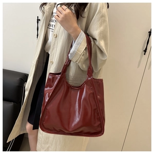 Detail of burgundy glossy patent leather tote bag with elegant shoulder straps