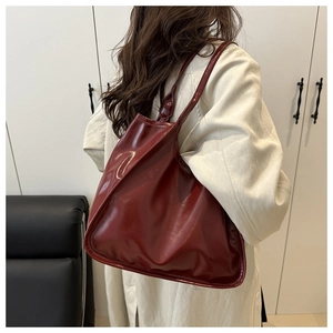 Detail view of glossy dark red patent leather tote bag with soft texture and shoulder strap