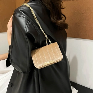 Kleine quadratische Tasche aus champagnerfarbenem Samt mit goldener Kette am Model