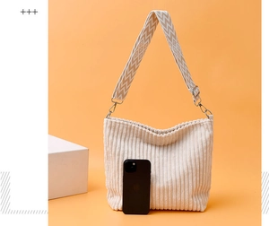 Détail du sac seau en velours côtelé blanc cassé avec bandoulière et téléphone de référence