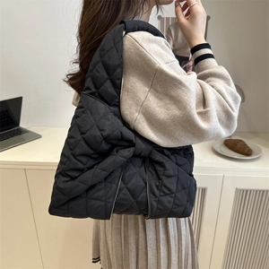 Quilted black puffer bag with large bow detail shown in a stylish side-view shoulder carry
