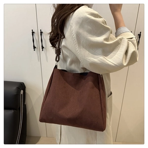 Détail d'un grand sac cabas en daim marron foncé avec bandoulière à nœud élégante