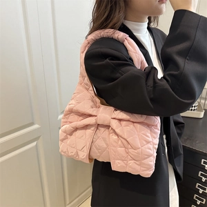 Pink quilted cloud bag with large bow and puffy padded design shown on a female model