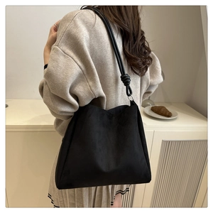 Détail du cabas noir givré minimaliste avec bandoulière nouée porté par le mannequin