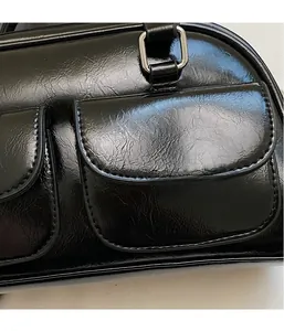 Detail of black glossy oil wax leather handbag with silver hardware and front pockets