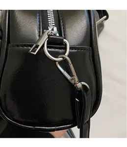 Macro shot of silver-tone hardware hook and D-ring on black patent leather handbag