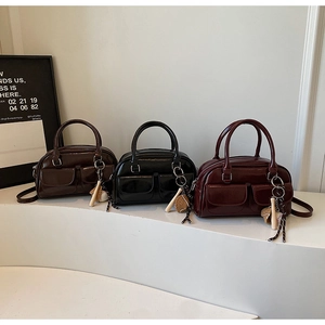 Detail of mini patent leather boston bags in brown black and burgundy with baseball charms