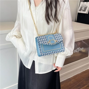 Élégant sac en tweed bleu clair avec chaîne et boucle dorée porté par un modèle