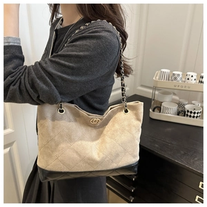 Détail du sac cabas beige matelassé avec bandoulière chaîne et fermoir doré sur un modèle