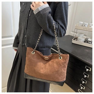 Détails d'un sac cabas en daim marron avec surpiqûres et bandoulière chaîne dorée