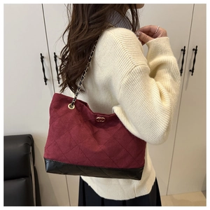 Détail d'un sac fourre-tout bordeaux matelassé avec bandoulière chaîne et base noire