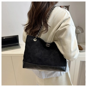 Détail d'un sac cabas noir matelassé avec chaîne dorée dans un décor de bureau chic