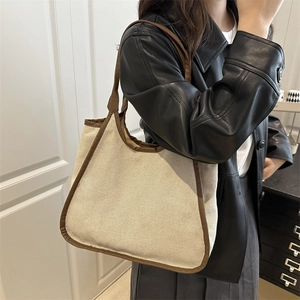 Minimalist canvas tote bag with brown leather trim shown on shoulder for daily commute