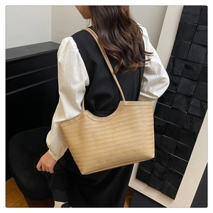 Detail of beige woven tote bag with herringbone pattern shown on model's shoulder