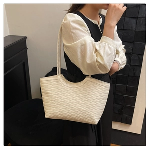 Detailed side view of white woven tote bag with herringbone texture on female model