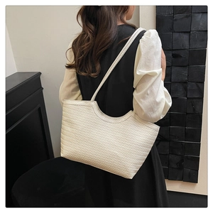 Detailed view of the woven texture and long strap of this stylish white tote bag