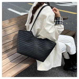 Macro detail of high-quality black woven leather texture on large capacity tote bag