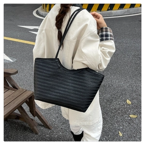 Detail of black woven tote bag featuring a chevron pattern and slim shoulder straps