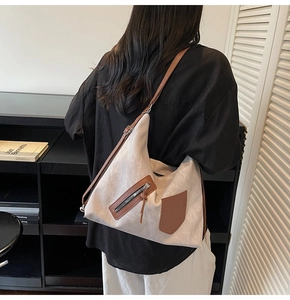 Detailed back view of a large canvas hobo bag with brown leather trim and silver zippers