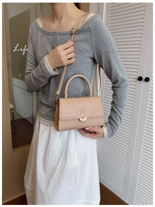 Detail of light beige crocodile pattern handbag with golden metal lock and top handle