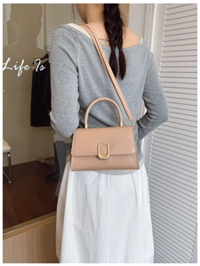 Detail of apricot crocodile texture bag with gold hardware worn as a shoulder bag