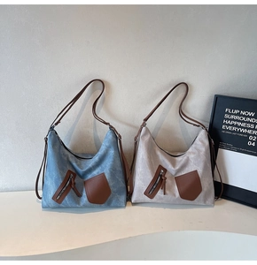 Detail view of large tote bags in washed blue and beige with brown leather pockets