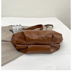 Detail of caramel brown gathered pleats on soft faux leather vintage shoulder bag