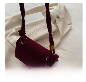 Detail of burgundy velvet crossbody bag featuring gold eyelets and knotted rope strap