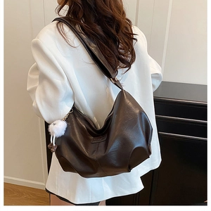 Detail of retro dark brown hobo bag with leather texture and white plush pendant accessory