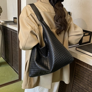 Fashionable black woven leather hobo tote bag worn by model for elegant autumn style
