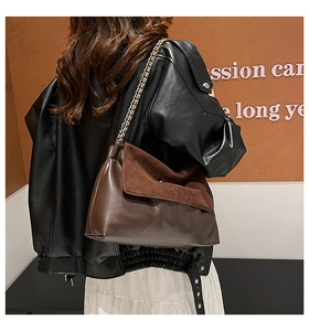 Detailed view of the brown leather chain shoulder bag worn by a fashion model outdoors