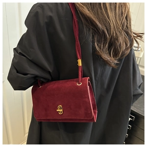 Detailed back view of a burgundy suede crossbody bag with gold rotating lock and strap