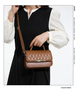 Brown quilted crossbody bag with metal bar detail and adjustable strap on a model