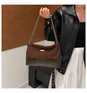 Detail of a brown patchwork shoulder bag with suede flap and elegant gold chain strap
