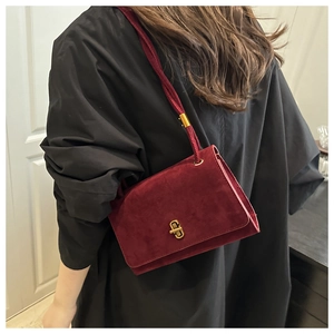 Detail view of burgundy velvet shoulder bag with vintage gold rectangular twist lock closure