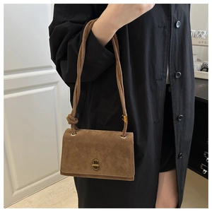 Close-up of brown suede evening bag featuring a vintage brass twist lock and knotted strap