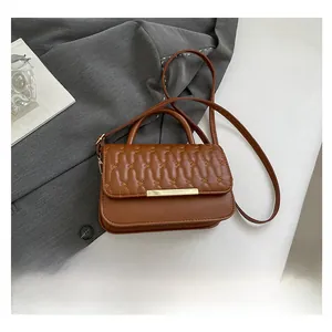Detalle del bolso acolchado marrón con costuras onduladas y detalle de barra metálica dorada