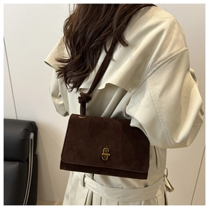 Detail of dark brown suede shoulder bag with gold metal twist lock and knotted strap