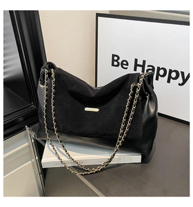 Detail of black patchwork leather shoulder bag with gold chain strap and fashion metal logo