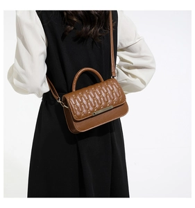Vista trasera de modelo con bolso bandolera acolchado marrón y detalles metálicos oro