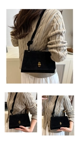 Detailed close-up of matte black faux suede texture and golden metal twist lock on the bag