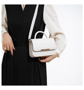 White quilted crossbody bag featuring elegant gold metal trim and fine stitching details