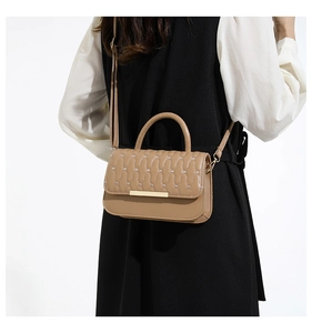 Detalle de bolso bandolera marrón claro con textura acolchada y cierre dorado en modelo