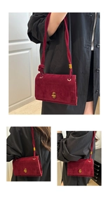 Detail of burgundy faux suede bag featuring a gold C-shaped metal lock and knotted strap